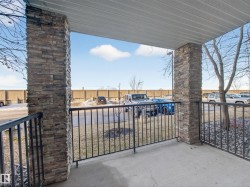 The property features a patio with concrete flooring, stone veneer columns, and a black metal railing - 