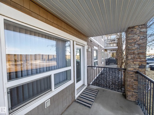 The property features an outdoor patio with a concrete floor, a decorative stone column, and black metal railings - 1111 9363 Simpson Drive, Edmonton, AB - Outdoor With Exterior