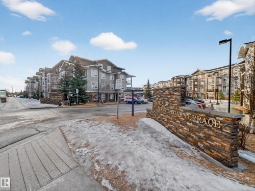 The property features a stone facade entrance sign, leading to a multi-story building with balconies - 1111 9363 Simpson Drive, Edmonton, AB - Outdoor