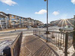 View of the property's exterior, featuring multi-story buildings with balconies, and a paved parking area - 