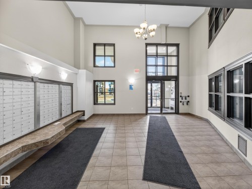 The property features a spacious entryway with tile flooring, high ceilings, large windows, and a classic chandelier - 1111 9363 Simpson Drive, Edmonton, AB - Indoor Photo Showing Other Room