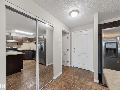 The entry features tiled flooring, a white paneled door, and a mirrored closet - 1111 9363 Simpson Drive, Edmonton, AB - Indoor Photo Showing Kitchen