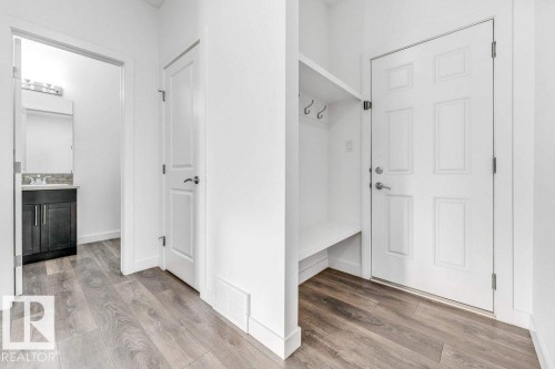 Entryway featuring durable flooring, a built-in bench with hooks for storage, and a white paneled door - 1912 27 Street Nw, Edmonton, AB - Indoor Photo Showing Other Room
