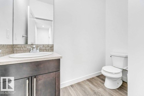 Bathroom featuring a dark wood vanity with a light-colored countertop, a white sink, and a mirror - 1912 27 Street Nw, Edmonton, AB - Indoor Photo Showing Bathroom