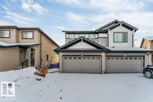 The property features a two-car garage, a light-colored siding exterior, and dark trim details - 1912 27 Street Nw, Edmonton, AB - Outdoor With Facade
