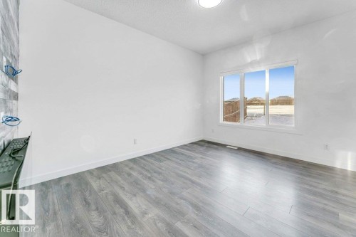 This bright room features wide plank flooring, a large window providing natural light, and a modern ceiling light fixture - 1912 27 Street Nw, Edmonton, AB - Indoor Photo Showing Other Room