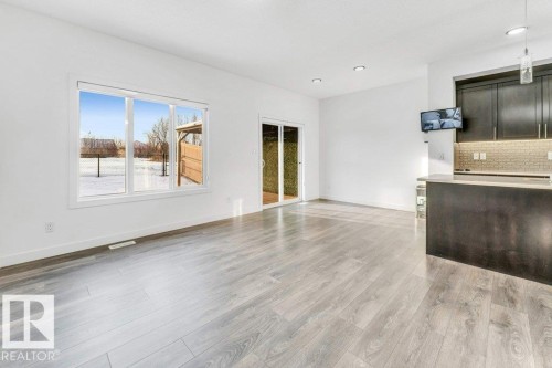 Open concept living space featuring light-toned flooring, a large window, and a sliding glass door - 1912 27 Street Nw, Edmonton, AB - Indoor Photo Showing Kitchen