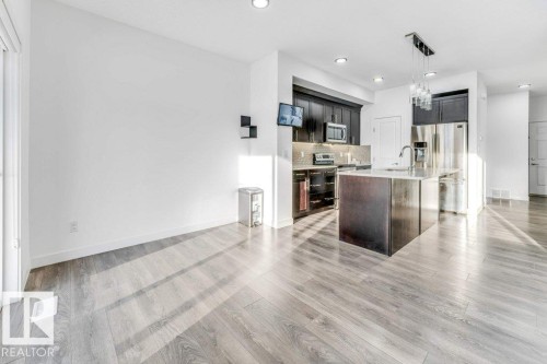The property features an open-concept living area with light-toned flooring, recessed lighting, and a kitchen island with a sink and modern pendant lighting - 1912 27 Street Nw, Edmonton, AB - Indoor Photo Showing Kitchen With Upgraded Kitchen
