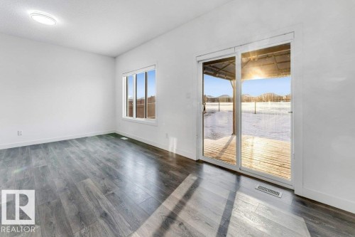 Bright room with wide plank flooring, a window, and sliding glass doors leading to an outdoor deck - 1912 27 Street Nw, Edmonton, AB - Indoor Photo Showing Other Room