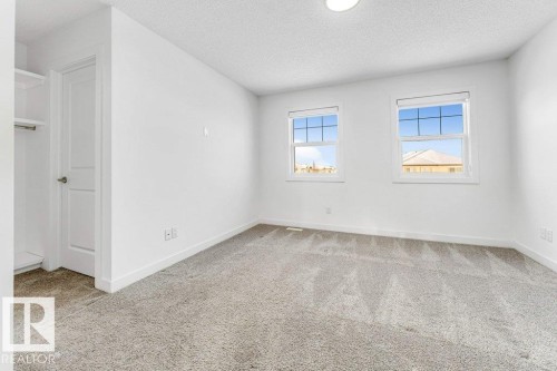 This bright room features two windows, light gray carpeting, and a closet with shelving and a hanging rod - 1912 27 Street Nw, Edmonton, AB - Indoor Photo Showing Other Room