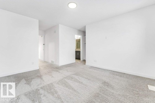 This space features light-colored walls, grey patterned carpeting, and a recessed ceiling light fixture - 1912 27 Street Nw, Edmonton, AB - Indoor Photo Showing Other Room