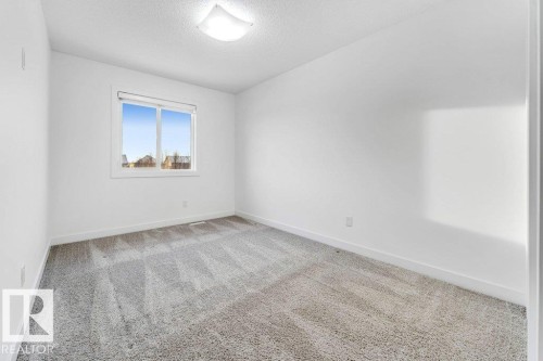 This room features light gray carpeting, a window providing natural light, and white walls with white baseboards - 1912 27 Street Nw, Edmonton, AB - Indoor Photo Showing Other Room