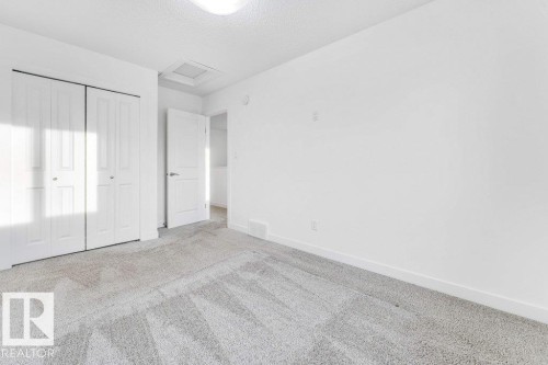 This room features light grey carpet, white walls, and white bi-fold closet doors - 1912 27 Street Nw, Edmonton, AB - Indoor Photo Showing Other Room