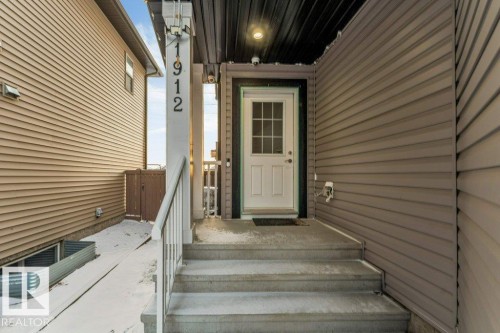 The property features light brown horizontal siding and a white front door with windowpanes - 1912 27 Street Nw, Edmonton, AB - Outdoor With Exterior