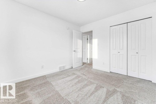 Bedroom with light grey carpet, white walls, and bi-fold closet doors - 1912 27 Street Nw, Edmonton, AB - Indoor Photo Showing Other Room