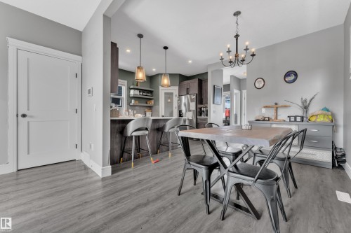 Open concept dining area with grey flooring, a chandelier light fixture, and a view of the kitchen with pendant lighting - 195 Kirpatrick Way, Leduc, AB - Indoor Photo Showing Dining Room
