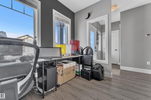 Room featuring dark gray walls, light wood-style flooring, a window with white trim, and a white door with a black doorknob - 195 Kirpatrick Way, Leduc, AB - Indoor