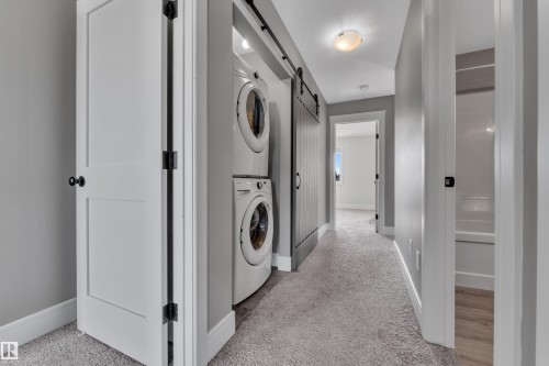 Laundry area featuring a stackable washer and dryer, with a barn door style enclosure - 195 Kirpatrick Way, Leduc, AB - Indoor Photo Showing Laundry Room