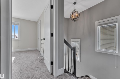 Carpeted room with a window providing natural light, white trim, and a white door with black hardware - 195 Kirpatrick Way, Leduc, AB - Indoor Photo Showing Other Room