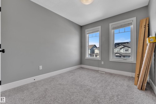 This room features two windows, a light gray carpet, and light gray walls with white baseboards - 195 Kirpatrick Way, Leduc, AB - Indoor Photo Showing Other Room