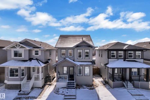 This property features a multi-story design with a dark shingle roof, light-colored siding, and a front porch - 195 Kirpatrick Way, Leduc, AB - Outdoor With Facade
