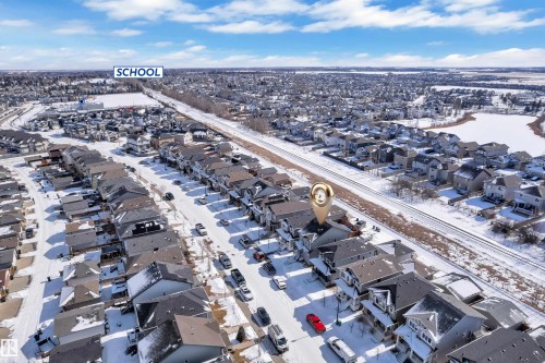 Aerial view of the property and its surrounding neighborhood, showcasing nearby residential areas, a school, and a body of water - 195 Kirpatrick Way, Leduc, AB - Outdoor With View