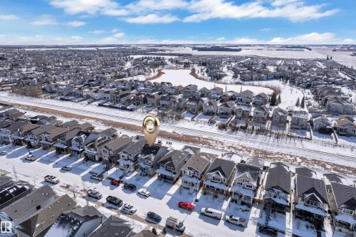 This aerial view highlights the property's location within a developed residential area, featuring a row of properties with pitched roofs and front-facing driveways - 195 Kirpatrick Way, Leduc, AB - Outdoor With View