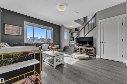 Living area featuring grey walls, large windows, and grey wood-style flooring - 195 Kirpatrick Way, Leduc, AB - Indoor Photo Showing Living Room
