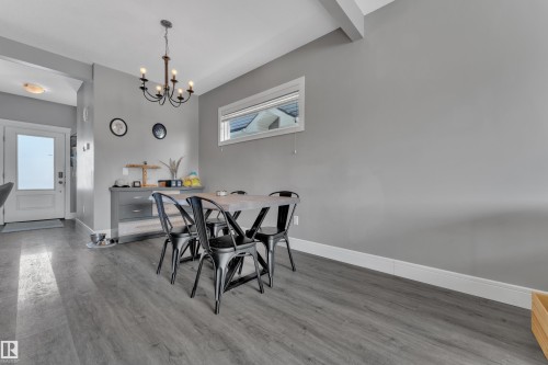 This room features gray plank flooring, a window providing natural light, and a white entrance door with frosted glass - 195 Kirpatrick Way, Leduc, AB - Indoor Photo Showing Dining Room