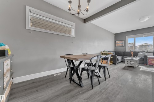 Open concept living space featuring a dining area with a chandelier and a living room with large windows - 195 Kirpatrick Way, Leduc, AB - Indoor Photo Showing Dining Room