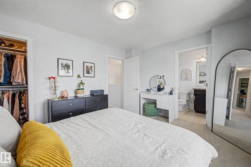 Bedroom with light carpet, a textured ceiling, and a spacious closet - 4110 Allan Crescent, Edmonton, AB - Indoor Photo Showing Bedroom