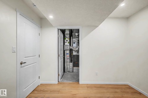Corridor featuring light wood-style floors, heating unit, a textured ceiling, and recessed lighting - 4110 Allan Crescent, Edmonton, AB - Indoor Photo Showing Other Room