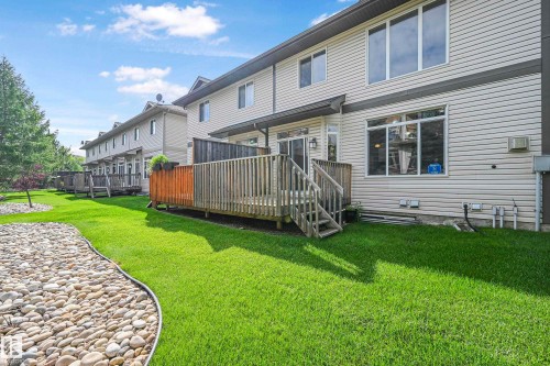 The property features a private wooden deck with stairs leading to a well-maintained lawn, bordered by a decorative rock bed - 11544 11 Avenue, Edmonton, AB - Outdoor