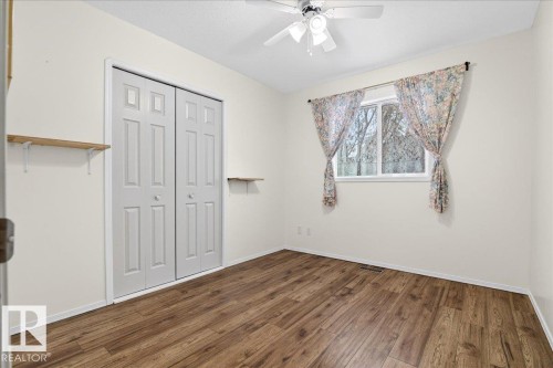 This room features hardwood-style flooring, a window offering views of trees, and a ceiling fan - 4412 Yeoman Close, Onoway, AB - Indoor Photo Showing Other Room