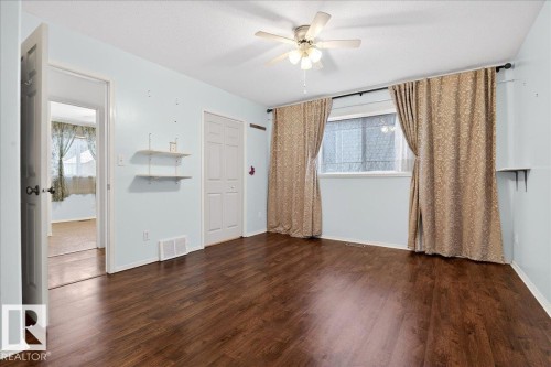 This room features dark hardwood flooring, light blue walls, a ceiling fan, and a window with light-colored curtains - 4412 Yeoman Close, Onoway, AB - Indoor Photo Showing Other Room