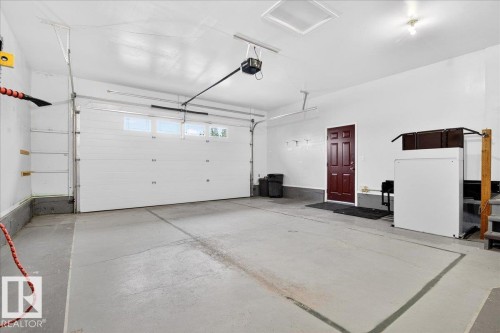 Attached garage featuring a white overhead door with windows, concrete flooring, and a dark wood interior door - 4412 Yeoman Close, Onoway, AB - Indoor Photo Showing Garage