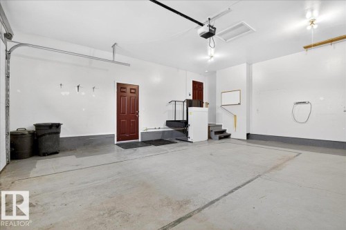 Spacious garage with light grey concrete flooring, white walls, and a dark brown door - 4412 Yeoman Close, Onoway, AB - Indoor Photo Showing Garage