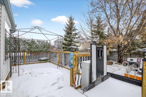 Expansive outdoor deck with a metal gazebo frame and wooden railings, overlooking a yard with mature trees - 4412 Yeoman Close, Onoway, AB - Outdoor