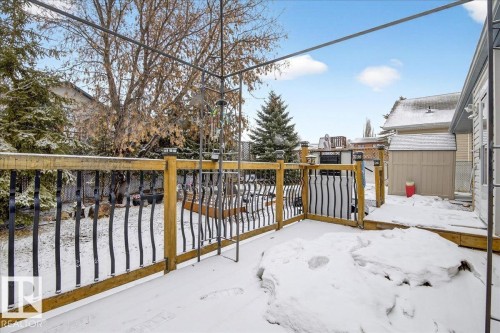 The property features a wood deck with a metal railing, overlooking a fenced yard with mature trees - 4412 Yeoman Close, Onoway, AB - Outdoor With Exterior