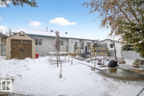 The property features a spacious rear yard with a wooden deck, a storage shed, and a paved area - 4412 Yeoman Close, Onoway, AB - Outdoor