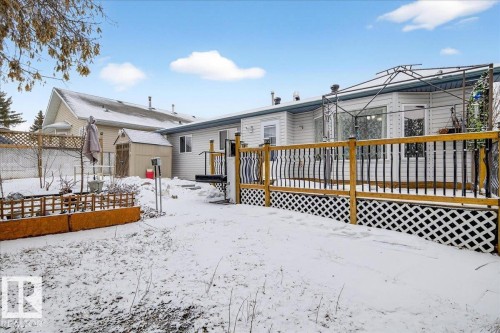 The property features a spacious deck with a wooden railing and lattice skirting, overlooking a snowy yard - 4412 Yeoman Close, Onoway, AB - Outdoor With Deck Patio Veranda