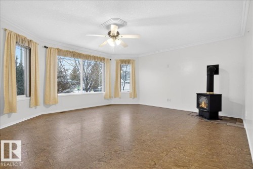 Living area with a wood-burning stove, bay windows, and a ceiling fan - 4412 Yeoman Close, Onoway, AB - Indoor