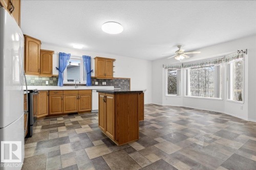 The kitchen and dining area showcase wood cabinetry, a practical kitchen island with a dark countertop, and a bay window providing natural light - 4412 Yeoman Close, Onoway, AB - Indoor Photo Showing Kitchen