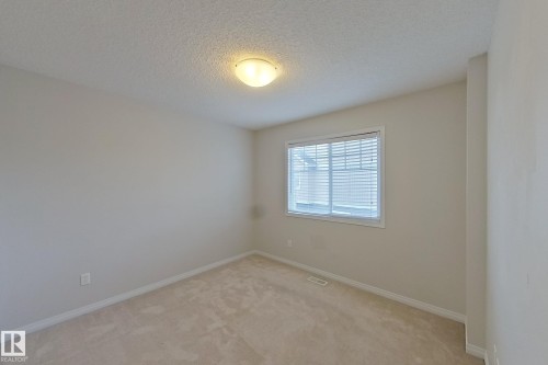 This room features light-toned carpeting, a window with blinds, and an overhead flush mount light fixture - 87 4050 Savaryn Drive, Edmonton, AB - Indoor Photo Showing Other Room
