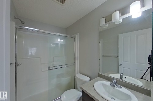 Well-appointed bathroom featuring a shower with sliding glass doors, a vanity with an integrated sink and chrome faucet, and overhead lighting - 87 4050 Savaryn Drive, Edmonton, AB - Indoor Photo Showing Bathroom