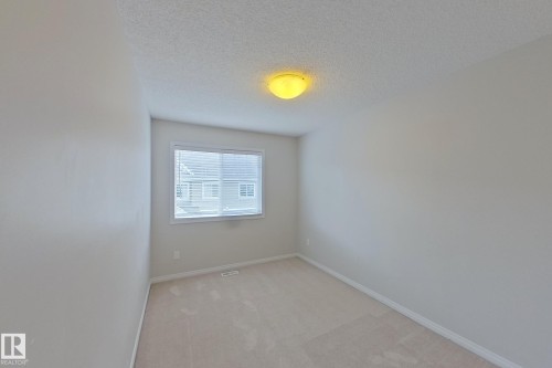 The room features light-colored carpeting, a window with horizontal blinds, and a flush mount ceiling light fixture - 87 4050 Savaryn Drive, Edmonton, AB - Indoor Photo Showing Other Room