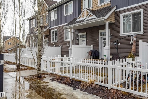 The property features a brown exterior with white window frames and a white picket fence - 87 4050 Savaryn Drive, Edmonton, AB - Outdoor