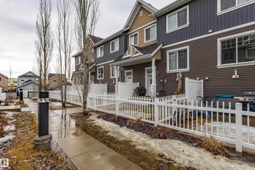 The property features a private patio area with a white picket fence, providing an ideal outdoor space - 87 4050 Savaryn Drive, Edmonton, AB - Outdoor With Deck Patio Veranda