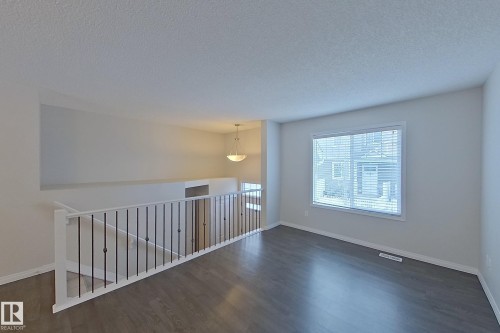 The property features an open living area with dark flooring, light-colored walls, and a window with blinds - 87 4050 Savaryn Drive, Edmonton, AB - Indoor Photo Showing Other Room