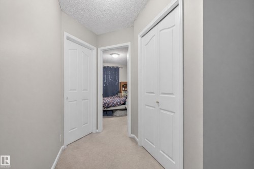 This hallway features neutral-toned walls, carpeted flooring, and white paneled doors - 8109 85 Street, Edmonton, AB - Indoor Photo Showing Other Room